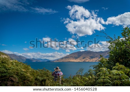Person with hat takes a picture of lake Wanaka in New Zealand