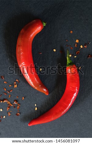 Two hot chili peppers on grey marble background. use for arabic sauce harissa, georgian sause adjika. Italian bio peperoncino by Calabria, top view Royalty-Free Stock Photo #1456081097