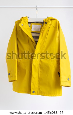 Yellow raincoat hanging on a shoulders (hanger) isolated on a white background/ Baby clothes Royalty-Free Stock Photo #1456088477