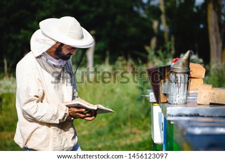 Beekeeper working in his apiary and looking to his bee diary