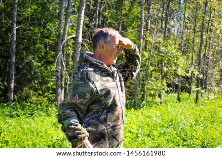 photo of an elderly man in the woods in a clearing.time year summer.
