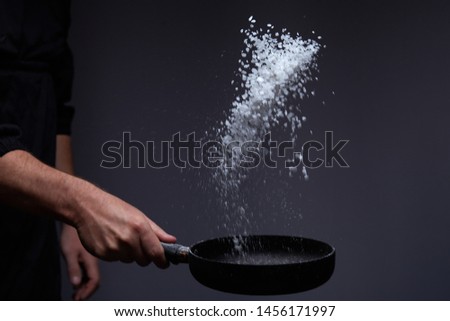 Cooking roasted aromatic salt in a pan by chef hand.Horizontal photo view. Dark black background with copy text area.