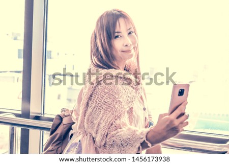 Beautiful young Travelling Asian Woman with Clean, Fresh, Glow, and pefect Skin selfie with mobile phone at international airport.