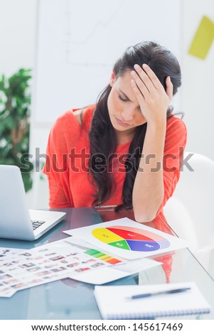 Annoyed designer sitting behind her desk holding her head