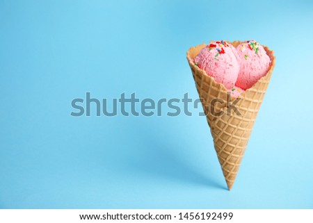 Delicious ice cream in wafer cone on blue background. Space for text