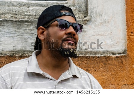 bearded man 30 to 40 years, with flowers in his beard. Closeup portrait of one handsome smiling man with long black beard showing on small many white flowers with sunglasses on a sunny day