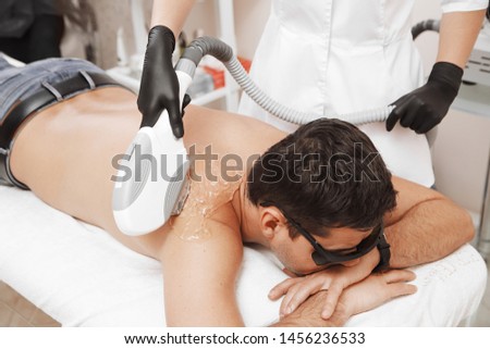 The man came to the procedure of laser hair removal. The doctor treats his neck and face with a special apparatus. Royalty-Free Stock Photo #1456236533