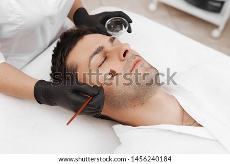 Cleaning the face of a man in a beauty salon. Retinol peel with brush. Acid organic peeling. Royalty-Free Stock Photo #1456240184