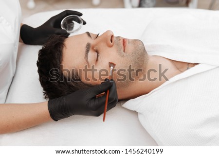 Cleaning the face of a man in a beauty salon. Retinol peel with brush. Acid organic peeling. Royalty-Free Stock Photo #1456240199