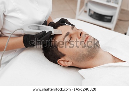 Skin care of ultrasound facial peeling. Ultrasonic cleansing procedure. Crop of beauty treatment of man. Beauty skin care cosmetology in spa salon.  Royalty-Free Stock Photo #1456240328