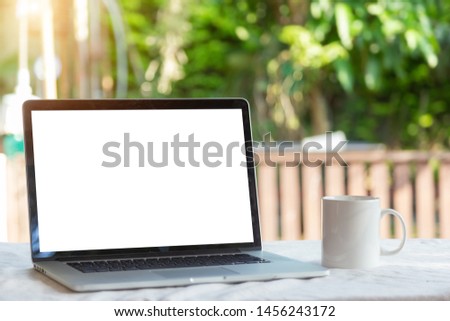 Laptop with blank screen with coffee cup on table in nature background , Laptop with blank white screen in blurred garden background , Outdoor office, Working outdoors concept