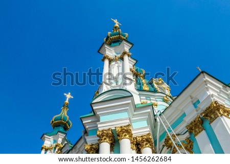 Side of the St Andrew's Church, Kiev, Ukraine. The church is small and painted blue and white, with many decorations on it's facade. Picture taken from under the church. Clear and blue sky