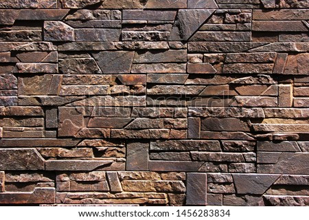The texture of the wall is made of crushed natural stone of dark brown color. Photo for wallpaper, concept of construction and natural natural building materials. Royalty-Free Stock Photo #1456283834