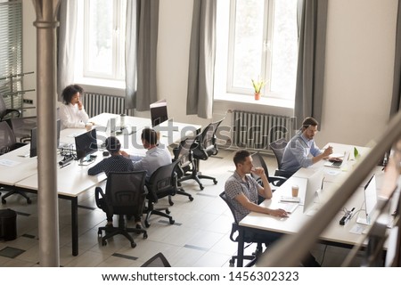 Top view of diverse people working together on computer performing daily routine tasks in coworking space, multiracial millennial men and women busy using devices discussing projects in shared office Royalty-Free Stock Photo #1456302323