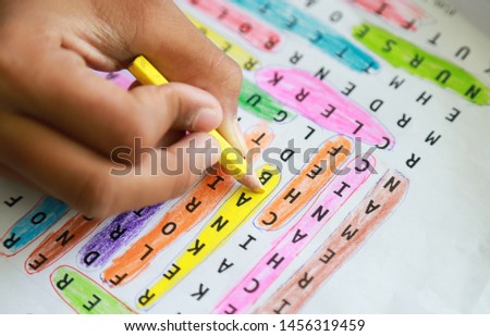 Student hand coloring yellow in doing learning word search activity. people daily life activity concept in educational 
