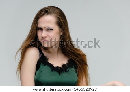 Concept close-up portrait of a pretty girl, young woman with long beautiful brown hair in a green t-shirt on a white background. In the studio in different poses showing emotions.