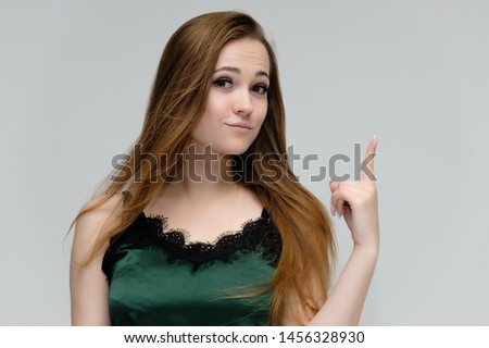 Concept close-up portrait of a pretty girl, young woman with long beautiful brown hair in a green t-shirt on a white background. In the studio in different poses showing emotions.