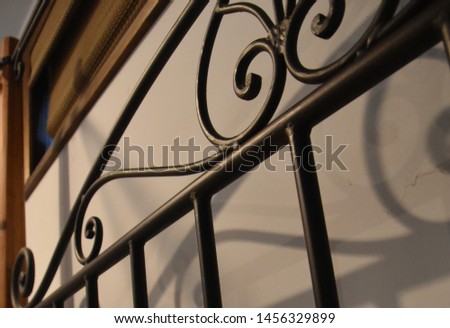 rod iron scroll decor on bed frame with scroll shadows on gray wall