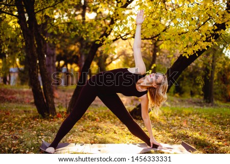 Flexible woman old age doing yoga in the autumn park