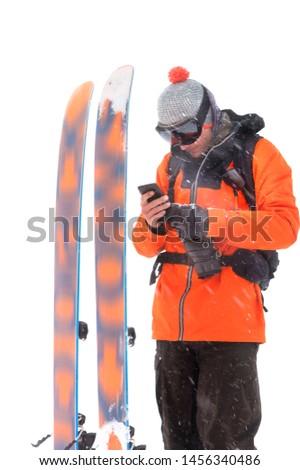 Portrait of a professional athlete skier with a cell phone in his hands next to skis isolated on white background. Sport and communication