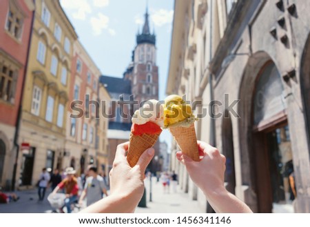 Women's hands with ice cream on the background of the city sights Mariatsky church in the historical center of Krakow, Poland, Europe, a famous tourist place
