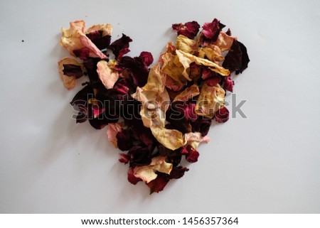 dried rose petals in heart shape on the white paper