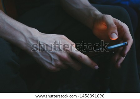 User of a smartphone. Side view shot of a man's hands using smart phone. Man's hands typing on phone.