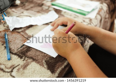 Cheerful cute kid having fun drawing a picture. Child`s hand is drawing with colorful pencils.