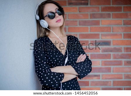 woman with headphones and sunglasses on brick wall background