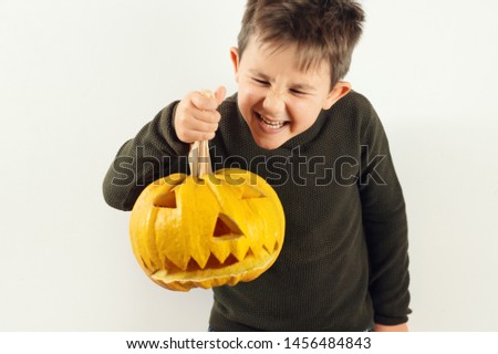 Happy Halloween Cute little boy making funny faces with a pumpkin.