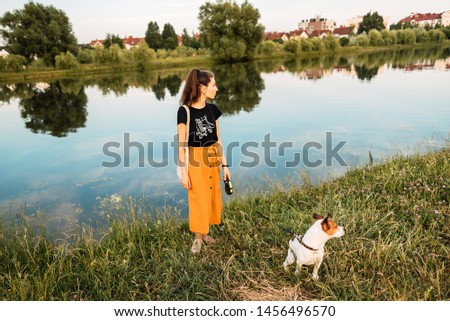 Happy beautiful young girl in dress with dog play in nature. Tinted and filtered photo. Modern youth lifestyle concept. man and animal together. little jack russell terrier