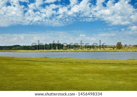 Lake on the golf course. Beautiful pheasant, blue cloudy sky, trees and bushes on the golf course.