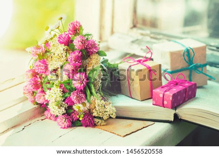 Bouquet of clover, gifts and a book on the window, toned.