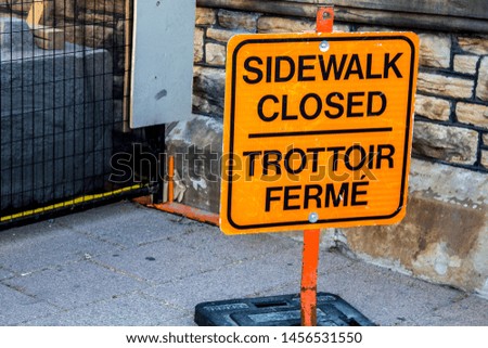 A temporary sign indicates that a sidewalk is closed for construction in both English and French.