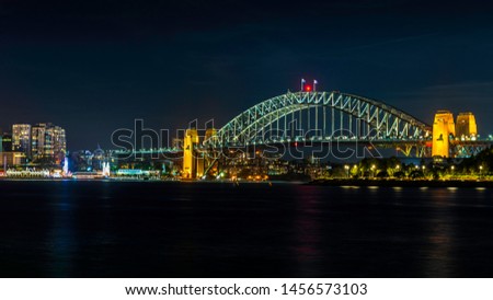 Night view of the iconic Sydney Harbour Bridge and the North Sydney suburb (left), from the Balmain East Wharf ferry terminal. Features plenty of colorful lighting with reflections from the water.