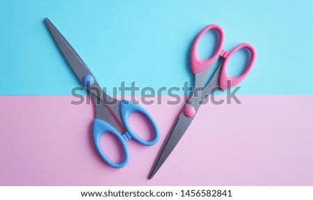 Two scissors of pink and blue.