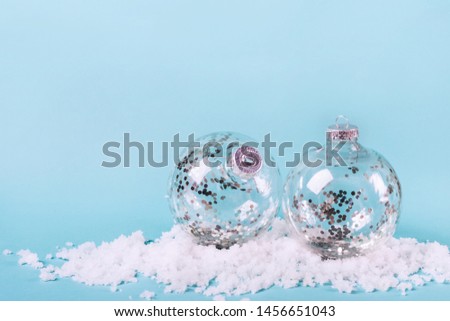 Transparent balls with silver confetti in snow. Minimalistic Christmas Concept.