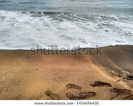 A picture of a beach in goa, india,with prints of footsteps on the sand