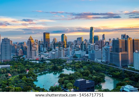 Lumpini Park and Bangkok city with colorful sky in sunset time. ( With flare of warm sunlight effect create reflection at the building and blur advertisement trademark, brand, logo.)