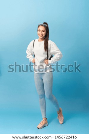 Full length photo of asian woman student walking with backpack isolated over light blue background