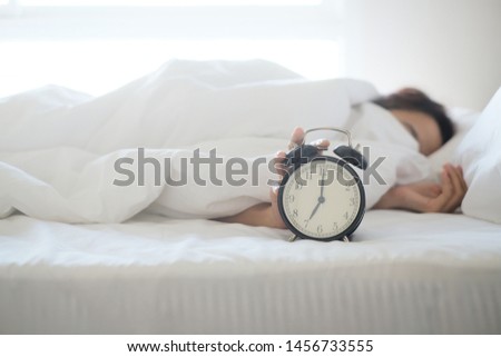 Woman sleep on the bed turns off the alarm clock wake up at the morning, Selective focus. Royalty-Free Stock Photo #1456733555