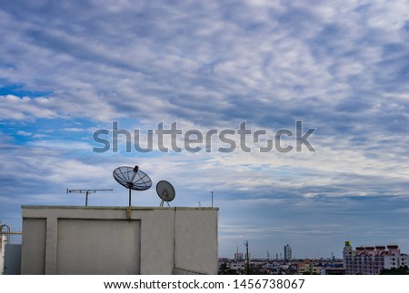 Satellite dish antenna on top of the building in urban area with cloudy sky