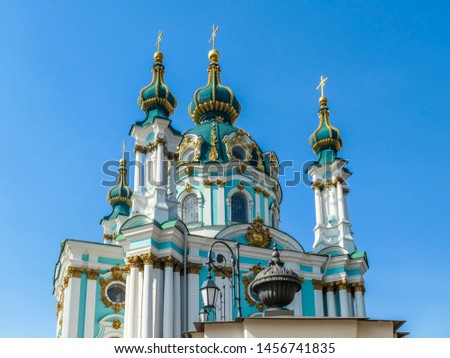 Front side of the St Andrew's Church, Kiev, Ukraine. The church is small and painted blue and white, with many decorations on it's facade. Picture taken from under the church. Clear and blue sky