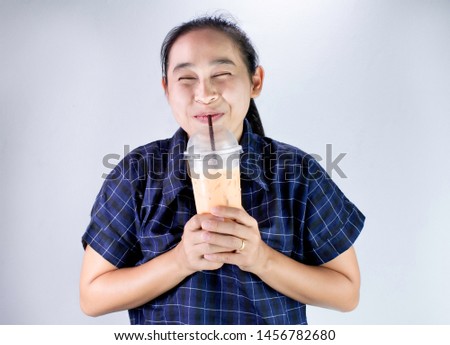 Happy Asian young woman is drinking Thai tea with milk. Popular beverage in Asia.
