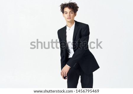 The guy in the white suit and with curly hair on a light background cropped look                           