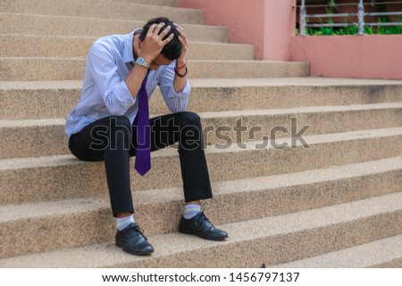 The hopeless man sits on the stairs, Desperate male company employee, Unemployment concept,Men who are stressed about finding work on the internet after being dismissed. Royalty-Free Stock Photo #1456797137