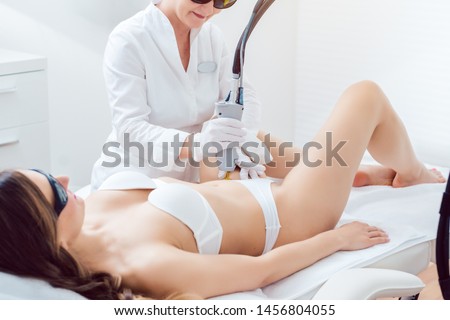 Hair removal in bikini zone using a laser device on young woman in cosmetic treatment