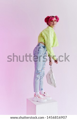 woman with pink hair stands on a cube