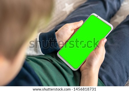 Phone a for keying is holding kid. Smartphone with a hromakey in the hands of a child.Smartphone with a green screen in hand child . top view close up