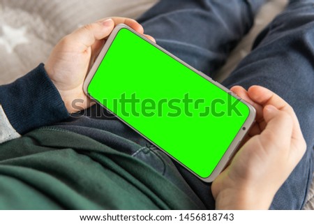 Smartphone with a hromakey in the hands of a child. Phone a for keying is holding kid top view close up. Smartphone with a green screen in hand child .